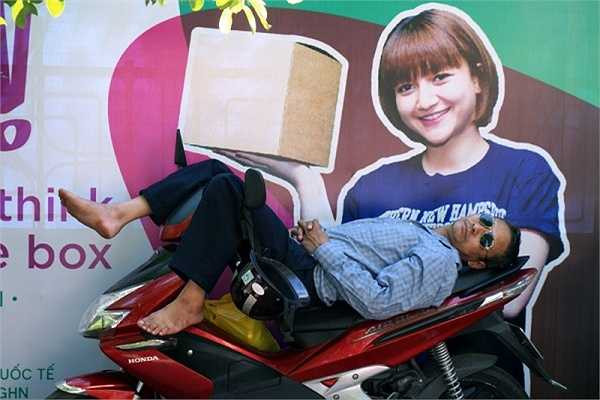 Tranh thủ đợi con, phụ huynh ngủ một giấc say ngay trên xe máy. (Ảnh: Lê Anh Dũng/ Vietnamnet)