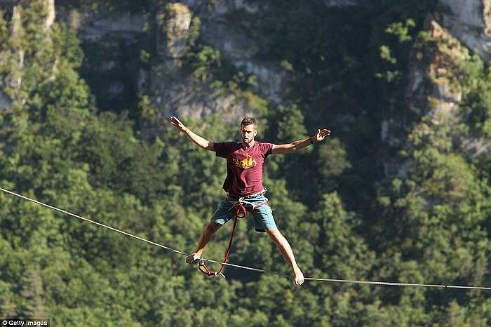 Paulin dang rộng hai chân, hai tay khi vắt vẻo trên sợi dây bắc qua hẻm núi sông Jonte, trong vườn quốc gia Cevennes, Pháp 