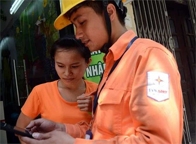 Nhân viên Công ty Điện lực Cầu Giấy Hà Nội cho một khách hàng trên phố Trần Đăng Ninh xem hình ảnh ghi số điện sáng 9/7