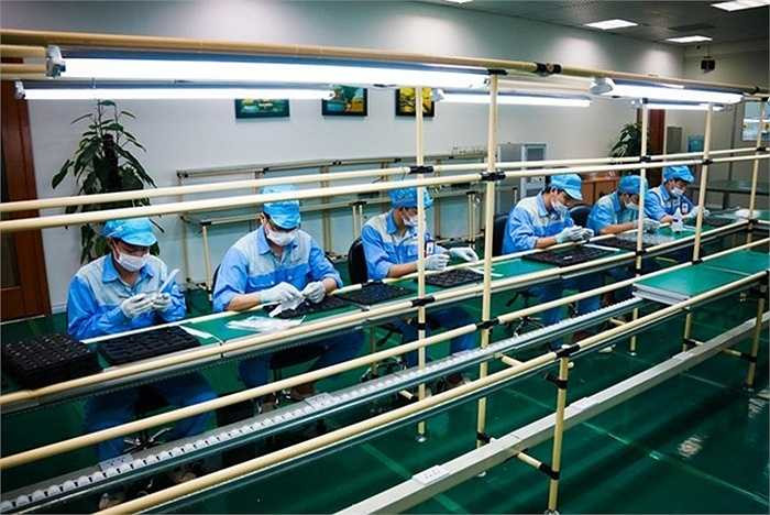 Tại nhà máy, công nhân ngồi trên những chiếc ghế xoay như ở văn phòng, trước mặt là dây chuyền lắp ráp với những hộp linh kiện.