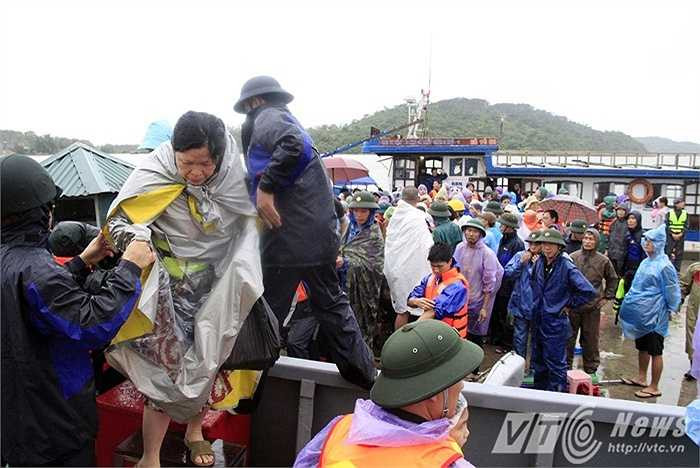 Cảnh du khách lên tàu để về đất liền dưới trời mưa lớn.