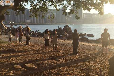 Những phụ nữ đứng trên bãi biển lúc hoàng hôn và nhìn thẳng vào mặt trời