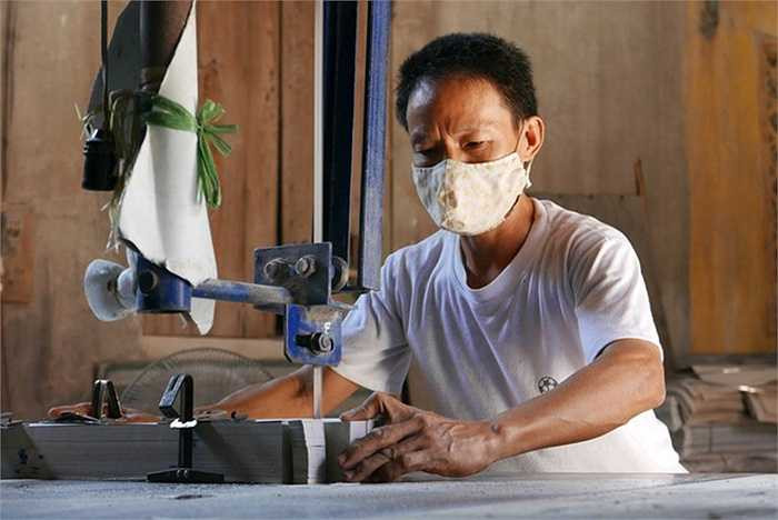 Anh Nguyễn Văn Mười dùng máy công nghiệp cắt giấy theo đường vẽ sẵn. Mỗi lượt cắt cho ra vài trăm tờ đều nhau tăm tắp, người đặt chỉ việc lấy về dán thành đồ mã thành phẩm.