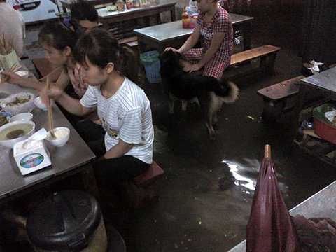 Một quán cơm ở phố Quan Nhân (Thanh Xuân, Hà Nội) bị ngập úng, thực khách vừa ăn cơm vừa phải nhúng chân xuống dòng nước bẩn. (Ảnh: Otofun)