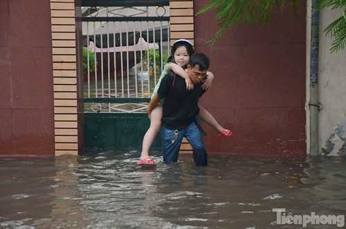 Một em nhỏ được người lớn cõng qua chỗ nước ngập. Một em nhỏ được người lớn cõng qua chỗ nước ngập.