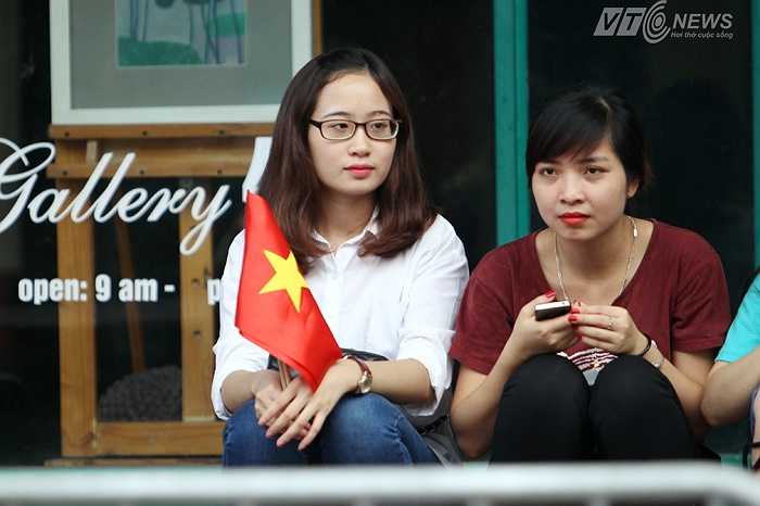 Các bạn trẻ ngồi chờ đợi đoàn diễu binh đi qua.