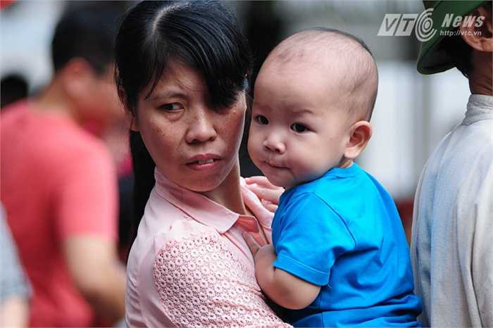 Em bé được mẹ bồng bế để xem diễu binh trong đám đông