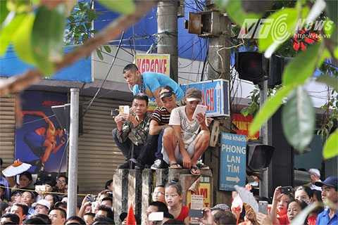 Người dân trèo lên trụ điện để xem diễu hành. 