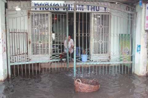 Một người dân tát nước từ nhà ra đường Ấp Chiến Lược - Ảnh: Đức Phú Một người dân tát nước từ nhà ra đường Ấp Chiến Lược - Ảnh: Đức Phú