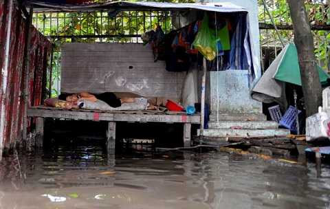 Một tiểu thương ngủ tại sạp bán hàng chờ nước rút - Ảnh: Hữu Khoa