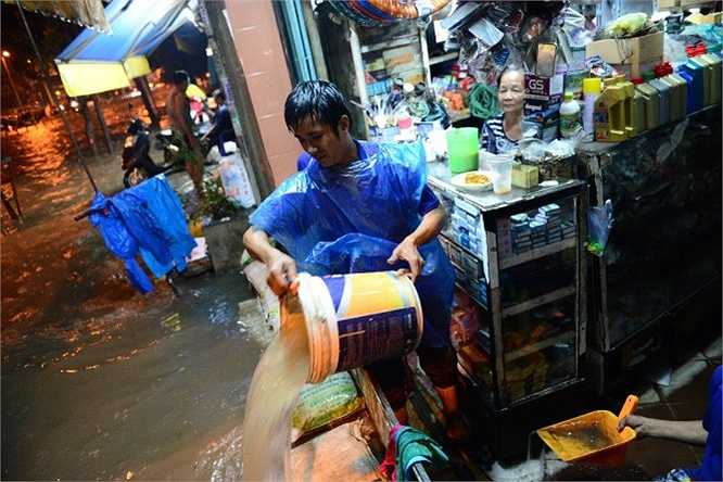 Anh Trần Hữu Nghĩa tát nước ra khỏi nhà -Ảnh: Thanh Tùng