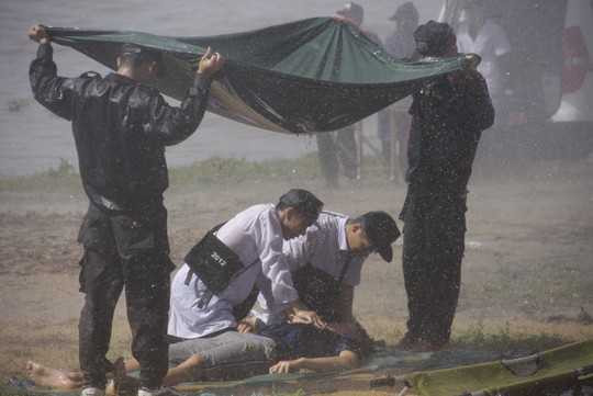 Lực lượng CSCĐ đứng che mưa để các bác sĩ sơ cứu người bị nạn khi bão đang đổ bộ