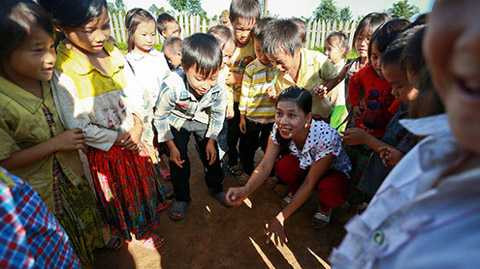 Cô giáo Lâm Thị Thu Thắm (lớp mầm non tại điểm trường thôn H’Mông) chơi đùa với các học sinh trên sân trường