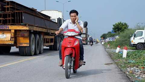 Đi ngược chiều, không đội mũ bảo hiểm vẫn nói chuyện điện thoại giữa dòng xe cộ đông đúc