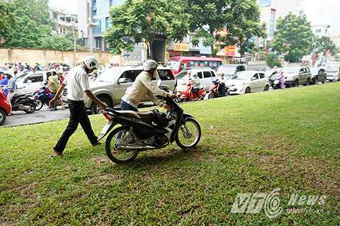 Nhiều người điều khiển xe máy còn vô ý thức dắt xe, đi xe trên thảm cỏ để tránh ùn tắc.