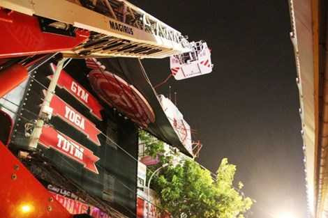 Người dân phải dựng dàn giáo để tháo dỡ những tấm biển đè lên dây cáp.