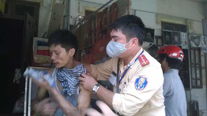 Lực lượng chức năng ngăn người đàn ông chuẩn bị lao vào đám cháy cứu tài sản - Ảnh: Duy Ngợi