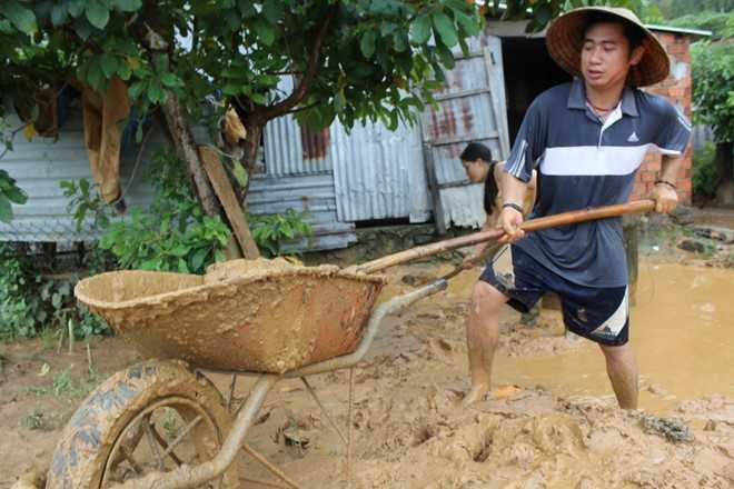 Người dân xúc đất ngập quanh giếng nước của xóm. (Ảnh: Hữu Long)