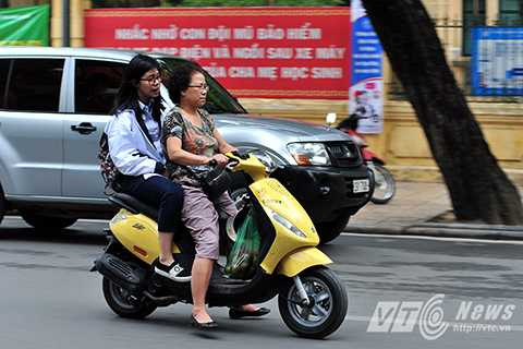 Một phụ huynh tới trường đón con nhưng cả hai đều không đội mũ bảo hiểm.