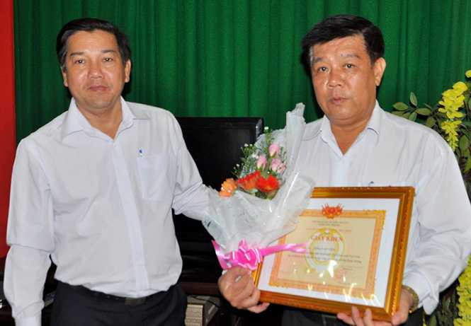 Ông Trịnh Minh Tự trao giấy khen và hoa cho ông Tống Văn Viên (phải) - Ảnh: Đức Thành