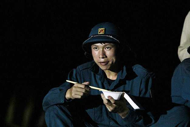 Một nhân viên cứu hộ tranh thủ ăn tối để chuẩn bị cho ca sau - Ảnh: Nam Trần