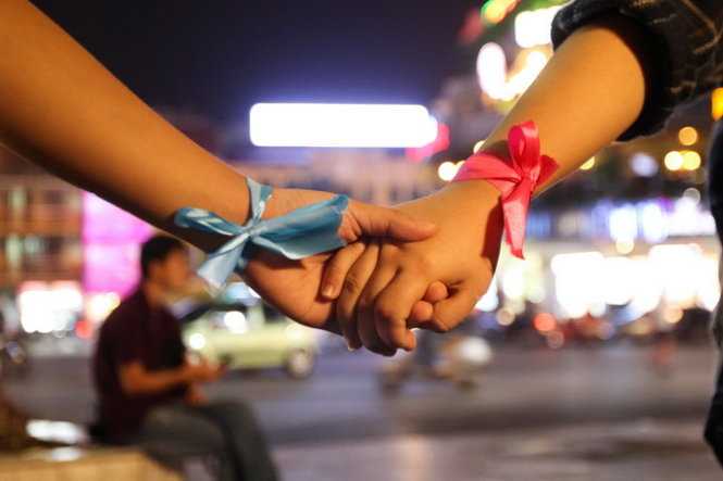 Hai bạn trẻ buộc trên tay miếng vải màu xanh và hồng tượng trưng màu sắc trong lá cờ của người chuyển giới - Ảnh: Nguyễn Khánh