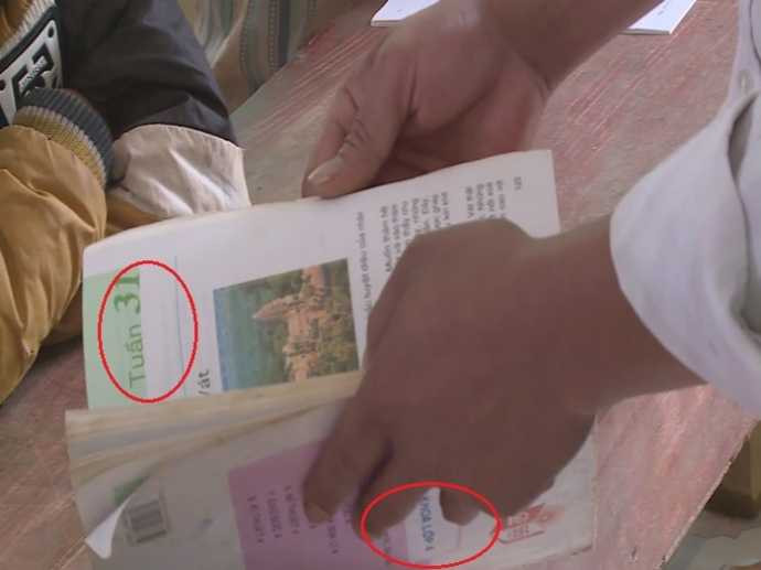 Cuốn sách có bìa bị dán ngược nên thầy giáo phải đảo lại trước khi đưa cho học trò đọc. (Ảnh cắt từ clip)