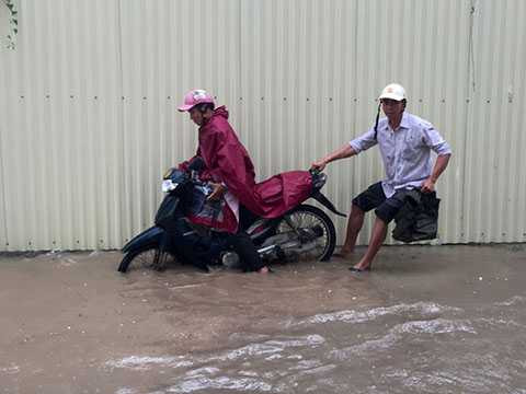 Một số người điều khiển xe máy đã bị ngã ra đường khi đi qua đoạn đường ngập.