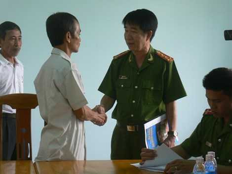 Đại tá Phạm Thật bắt tay công dân Huỳnh Văn Nén sau khi công bố, trao quyết định đình chỉ bị can. Ảnh: Phương Nam