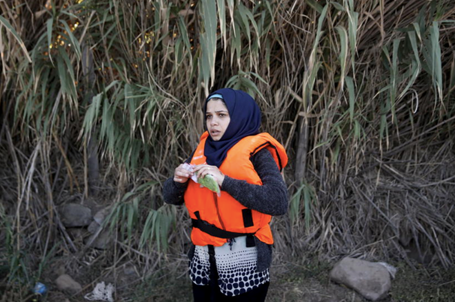 Một người tị nạn Syria mở túi bóng dùng để bọc điện thoại ngay sau khi đặt chân đến đảo Lesbos (Hy Lạp). Ảnh: Cnet.