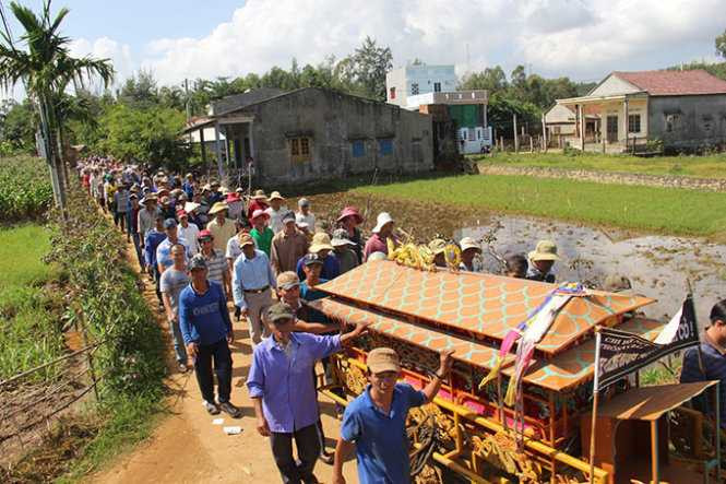 Những ngư dân kéo chiếc quan tài đi, phía sau là một đoàn người nối đuôi nhau đưa tiễn - Ảnh: Trần Mai