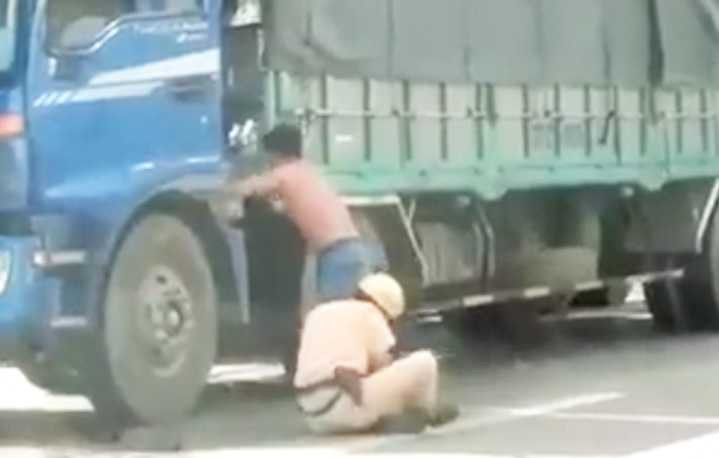 Cảnh thượng úy Thoại ngồi bệt xuống đường, cố ôm ghì chân tài xế Toàn trên xa lộ Hà Nội gây dư luận - Ảnh cắt từ clip