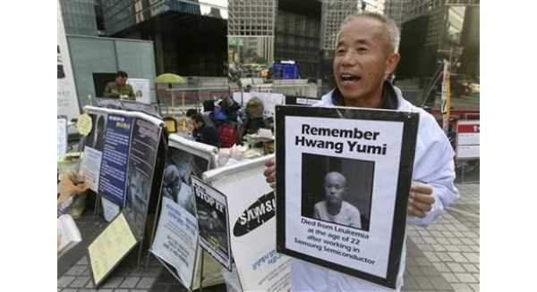 Ông Hwang Sang-gi cầm ảnh con gái qua đời vì nhiễm bệnh sau khi làm việc ở Samsung để phản đối tập đoàn ngày 23/10. Ảnh: AP