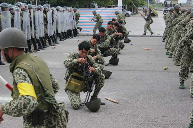 Lực lượng bộ đội hóa học khẩn trương đeo các thiết bị hỗ trợ phòng độc để làm nhiệm vụ khi đám đông biểu tình sử dụng bom khói tấn công