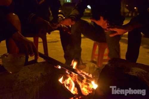 Những bàn tay hơ trên đống lửa để giữ ấm.