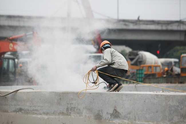 Phía tường bao của hầm chui, một số công nhân đang dùng máy để mài cho bề mặt bê tông bằng phẳng và lắp lan can.