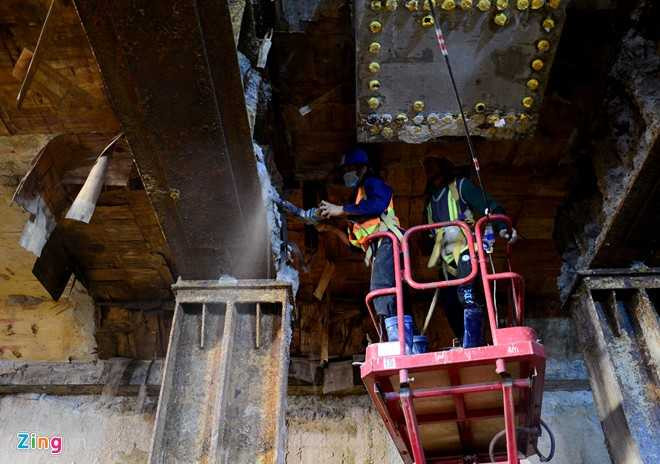 Công nhân dùng máy khoan thay nhau đẩy đất còn dính lại từ các trụ sắt tạm dùng để đỡ sàn.