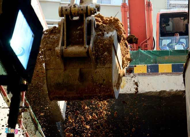 Chiếc xe cuốc trên mặt sàn vươn cánh tay cẩu dài cả chục mét xuống hầm B1 ngoạm từng khối đất lớn đổ lên thùng xe ben.