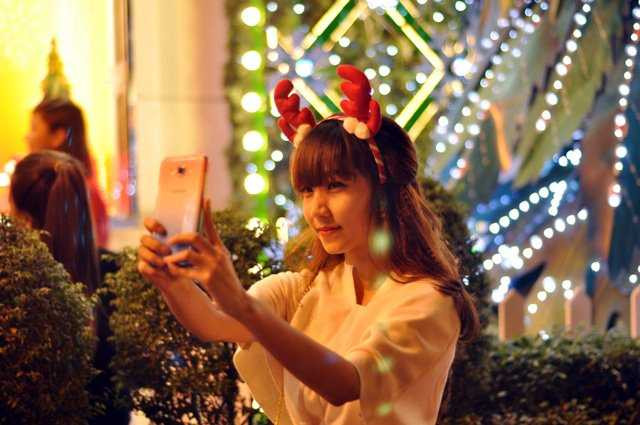 Thiếu nữ “tự sướng” với điện thoại di động trước tòa nhà Diamonds Plaza.