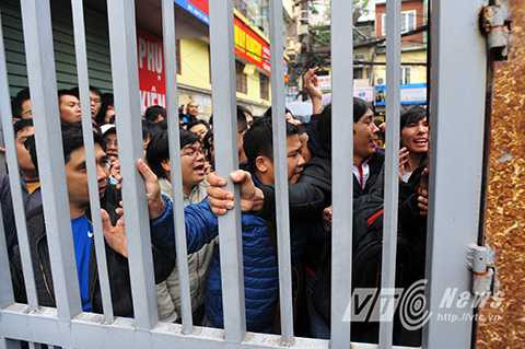 Cả dòng người chen nhau, những người hàng đầu phải gồng mình, chống tay vào cửa để chống lại sức ép từ phía sau.