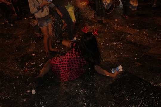 Một bé gái ngã xuống đất khi bị nhiều người khác đến xịt tuyết vào người.