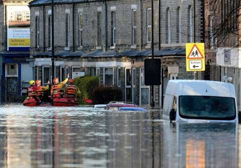 Nhân viên cứu hộ đang đi kiểm tra tình hình những người bị kẹt lại vùng lũ - Ảnh: PA