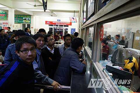 Tại quầy bán vé phía trong sảnh của bến xe, hàng dài người dân xếp hàng chờ mua vé xe về quê.