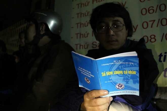 Trong lúc ngồi chờ, anh Trần Xuân Hoàng (quận Thanh Khê) tranh thủ đọc thông tin trong Sổ tiêm chủng cá nhân của con trai 6 tháng.