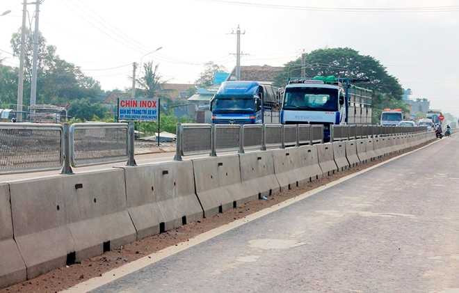 Người dân tự ý tháo tấm chống lóa trên dải phân cách quốc lộ. Ảnh: Minh Hoàng.