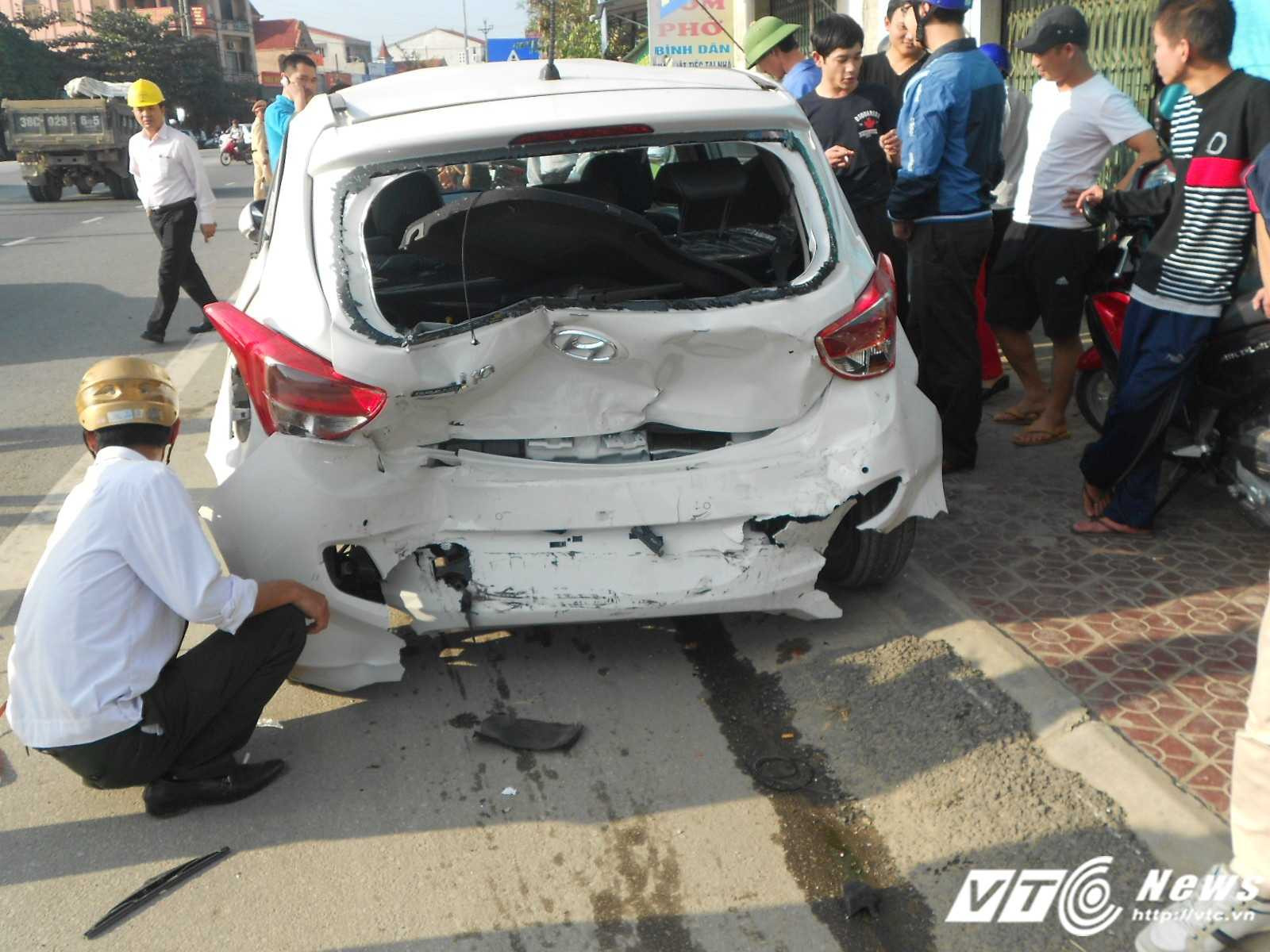 Chiếc xe ô tô màu trắng chưa đăng kí BKS bị xe điên húc biến dạng phần đuôi.