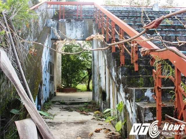 Bên ngoài và lối vào khán đài nhạc nước đổ nát, cỏ rêu bao phủ, hoang tàn và lạnh lẽo.