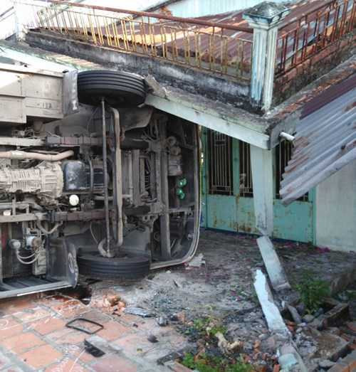 Chiếc xe ô tô khách lật nhào, lao vào nhà dân làm sập mái trước.