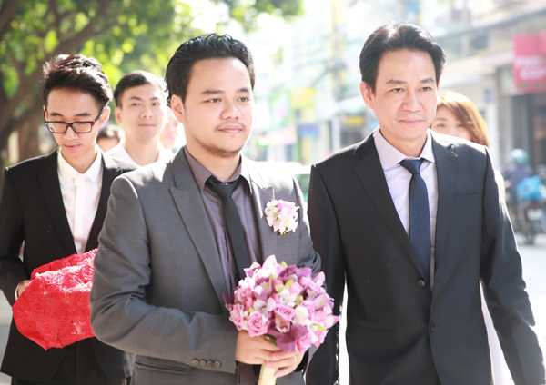 Đạo diễn Hoàng Duy mặc vest xám, cầm hoa cưới cùng người thân và đoàn bưng tráp quả nhà trai vào làm lễ xin dâu.