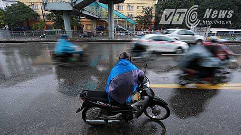 Để tránh mưa, rét, người lái xe ôm này chọn cách mặc thật nhiều lớp áo mưa và đứng chờ khách dưới chân cầu đi bộ. Tuy nhiên thời tiết giá rét khiến người dân lựa chọn di chuyển bằng taxi nhiều hơn khiến thu nhập của ông giảm đáng kể so với ngày thường.